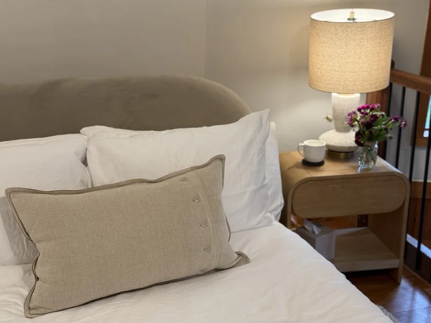 Loft bed with layered pillows and a softly lit bedside table.