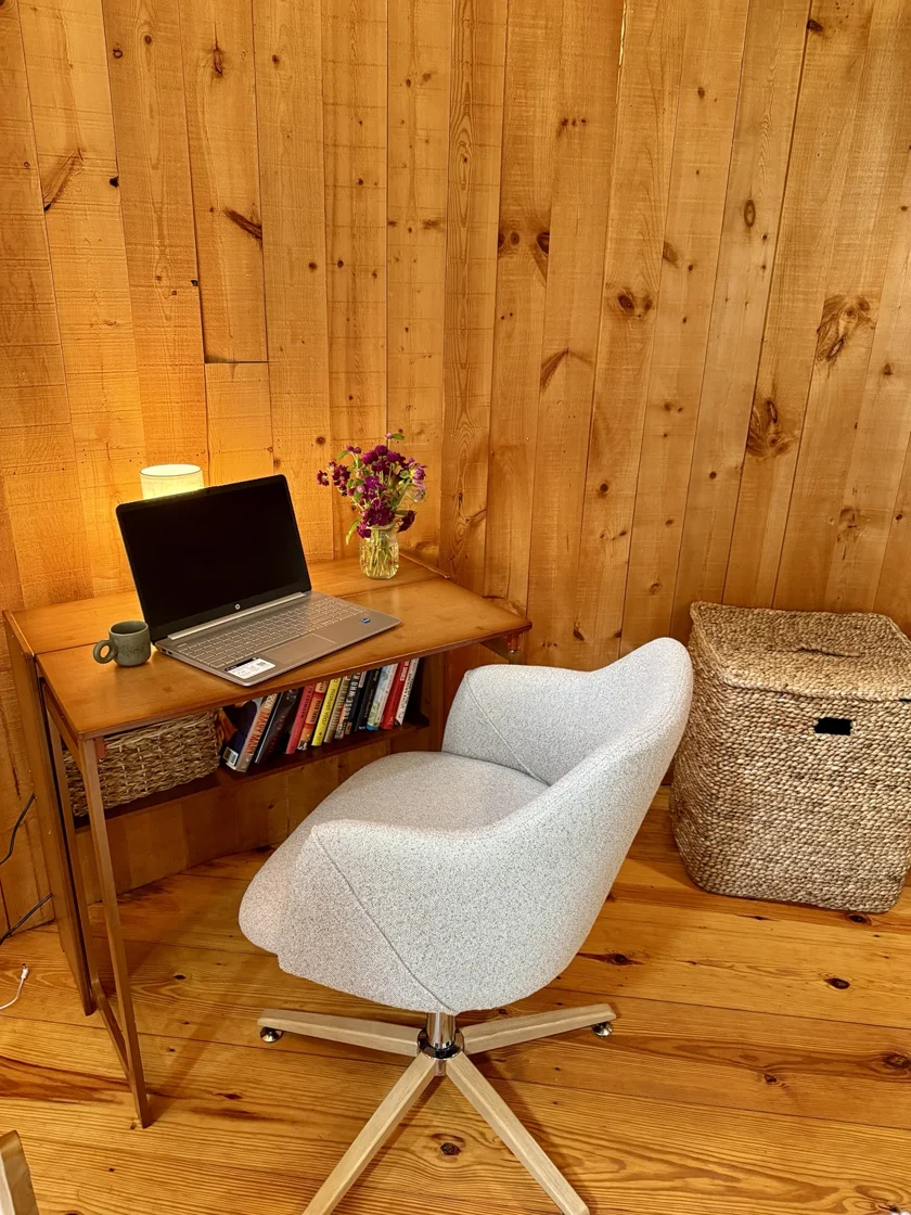 Compact wooden desk and upholstered chair beneath the stairs.